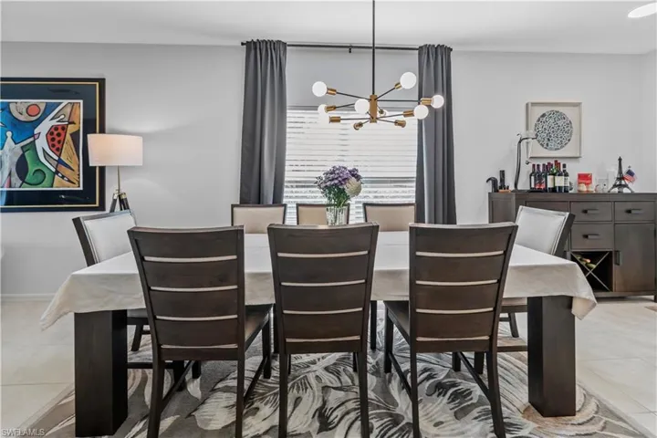 Dining area featuring a modern chandelier with spherical lights, a window with horizontal blinds and drapery, and wood-finish flooring