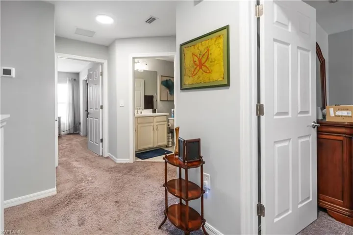 Hallway featuring neutral-toned carpet and light gray walls