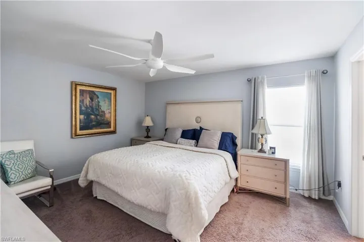 Carpeted bedroom with a multi-blade ceiling fan, a window with drapes, and a built-in closet door