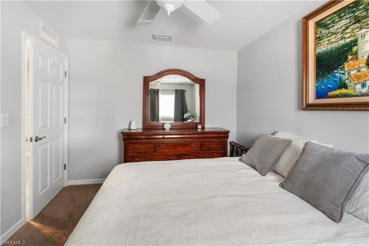 Bedroom featuring light gray walls, brown carpet flooring, and a white ceiling fan