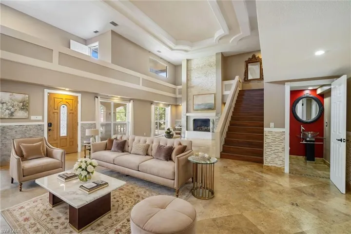Living room featuring a fireplace, a high ceiling, stairs, and a half bath