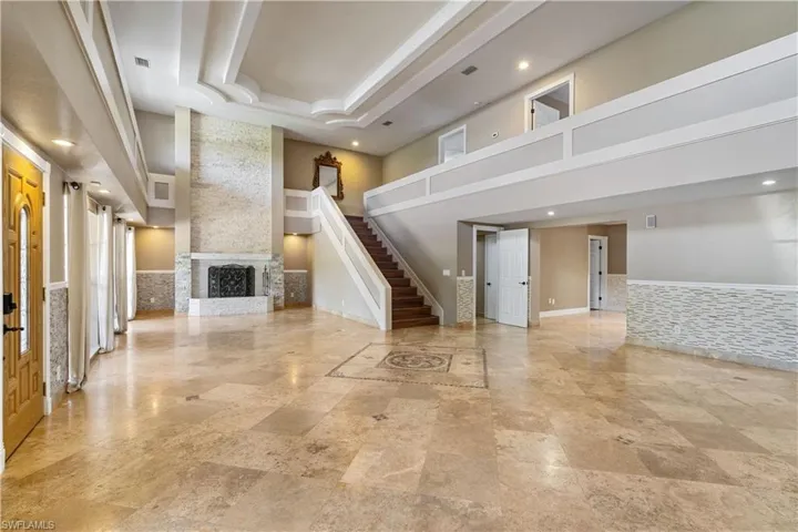 Unfurnished living room with stairway, recessed lighting, a large fireplace, a towering ceiling, and visible vents