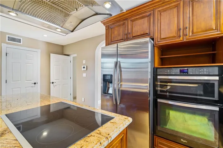 Kitchen with island, electric stovetop, and granite countertops