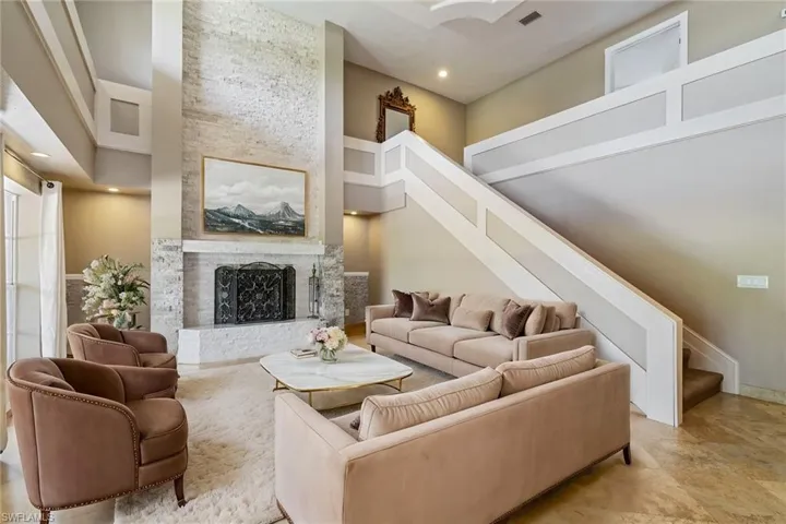 Living area with wood burning fireplace, high ceilings, and stairway