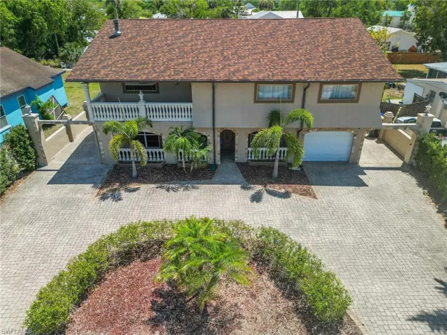 View of front facade with decorative driveway, a balcony, a garage, stucco siding, and roof with shingles