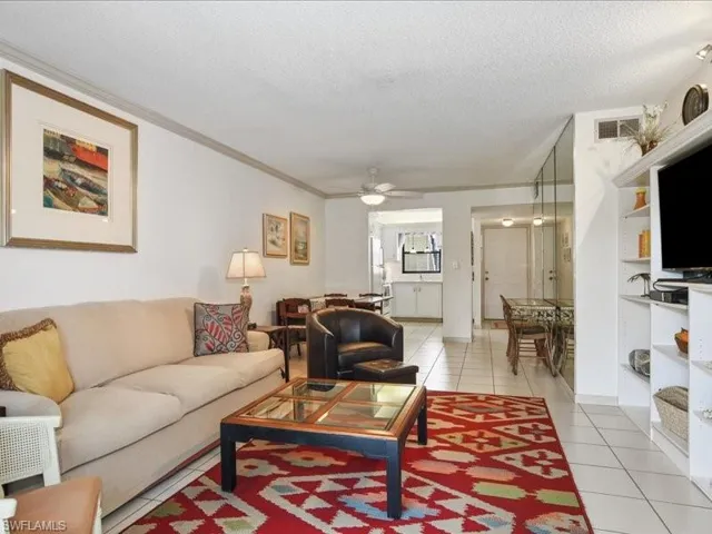 Tiled living room featuring ceiling fan, crown molding, and a textured ceiling