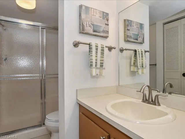 Bathroom featuring a shower with door, vanity, and toilet