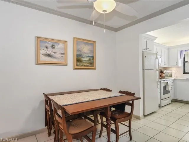 Tiled dining area with ceiling fan and ornamental molding