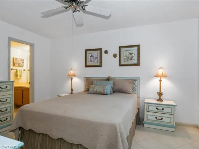 Bedroom with ceiling fan, light tile patterned floors, and ensuite bathroom