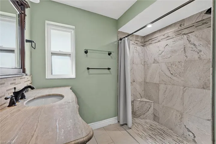 Bathroom featuring a beautiful tiled shower,  light tile patterned floors, and vanity