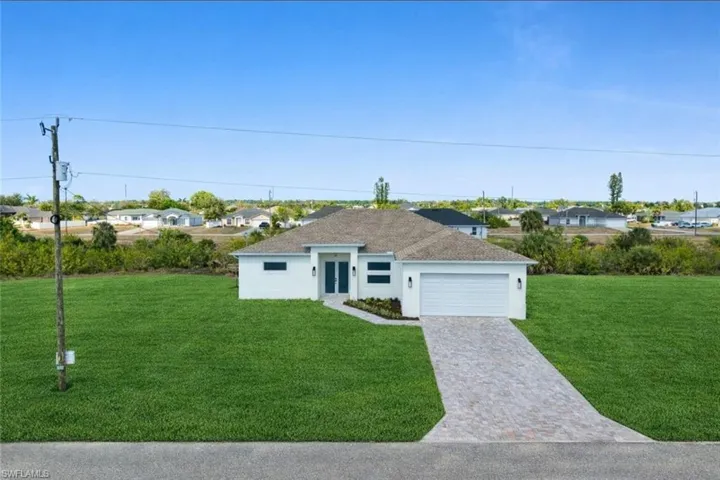 Ranch-style home featuring a residential view, a front yard, stucco siding, decorative driveway, and an attached garage