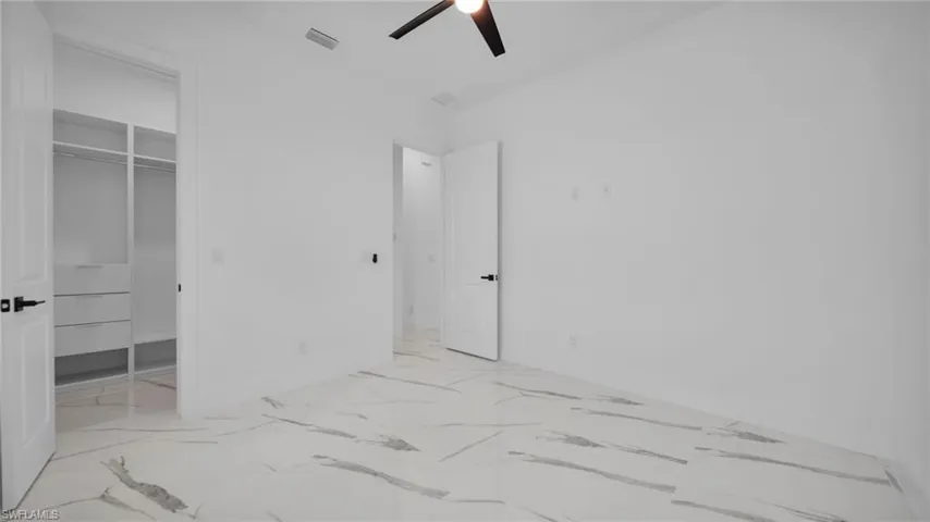 Unfurnished bedroom with a walk in closet and ceiling fan