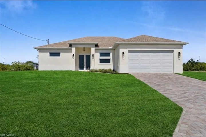 Prairie-style house featuring french doors, a front yard, stucco siding, and driveway