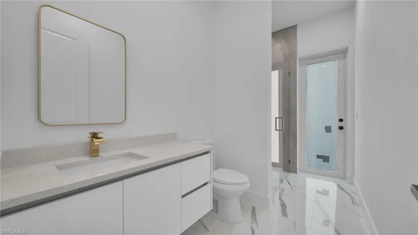 Bathroom featuring a marble finish shower, vanity, and light marble finish floors