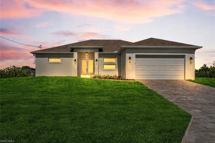 Prairie-style house with a yard, stucco siding, driveway, and an attached garage