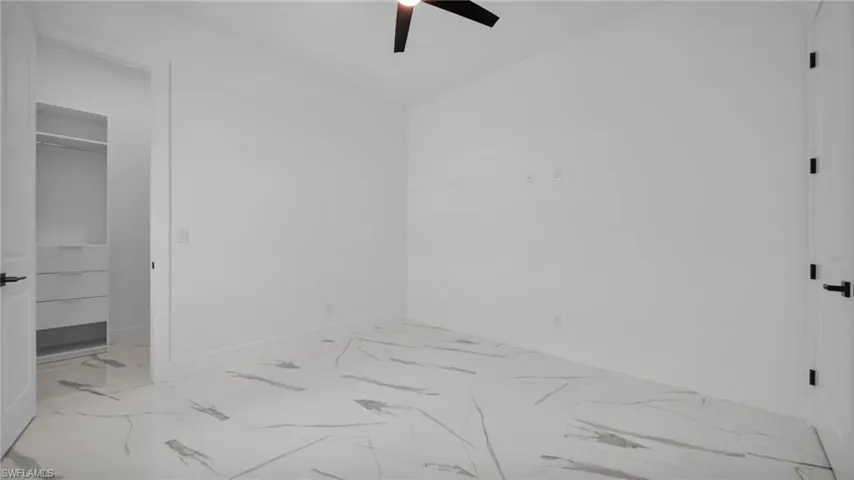Unfurnished bedroom with a spacious closet and a ceiling fan