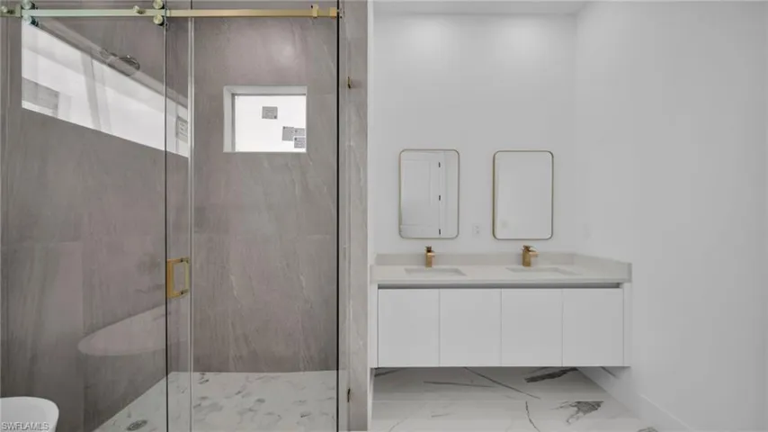 Bathroom with a marble finish shower and double vanity