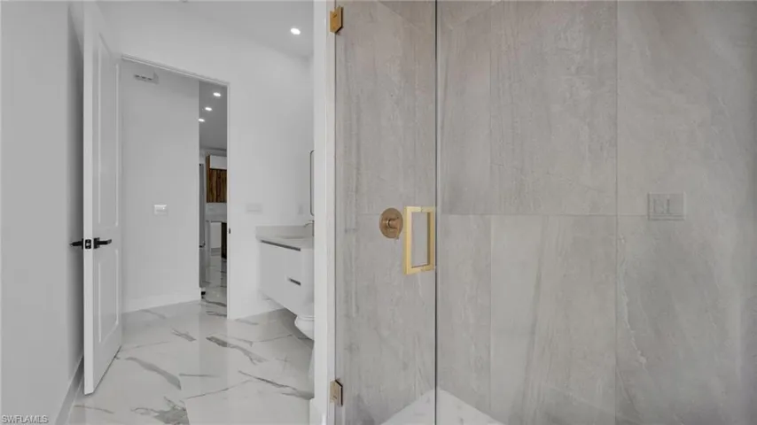 Full bathroom with vanity, recessed lighting, a marble finish shower, and light marble finish flooring