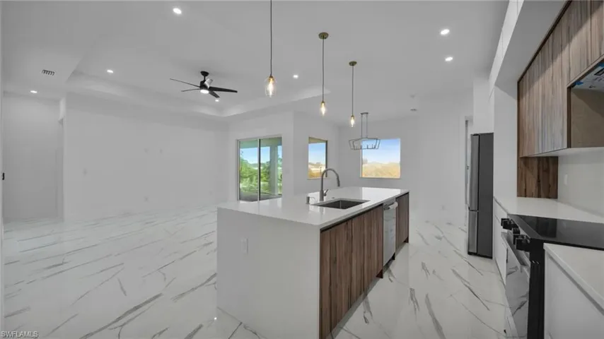 Kitchen with modern cabinets, open floor plan, dual tone cabinetry, light stone counters, and stainless steel appliances