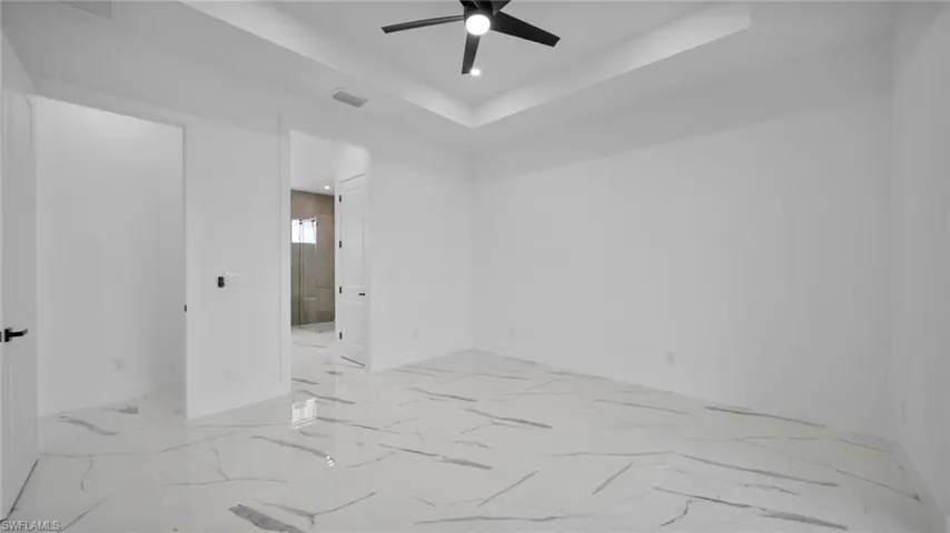 Empty room featuring a raised ceiling, a ceiling fan, and recessed lighting