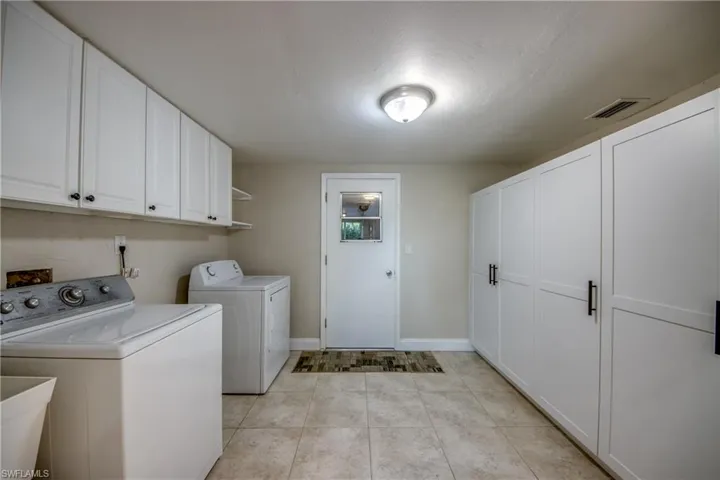 Laundry area featuring cabinet space, washing machine and dryer, and light tile patterned floors
