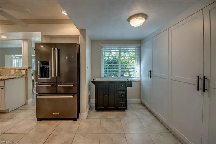 Kitchen with high end fridge, light tile patterned floors, a ceiling fan, and white cabinetry