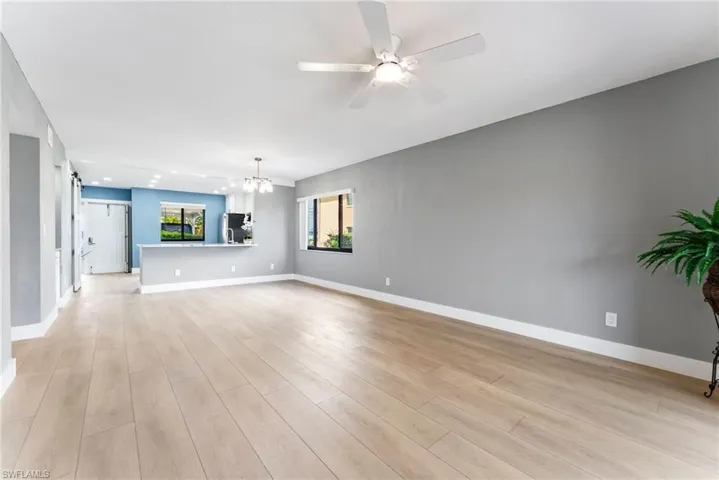 Light wood-finish flooring, recessed lighting, ceiling fan, and modern pendant light fixture