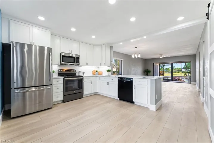 Kitchen featuring white cabinetry, stainless steel appliances, an island with a built-in dishwasher, and wood-finish flooring
