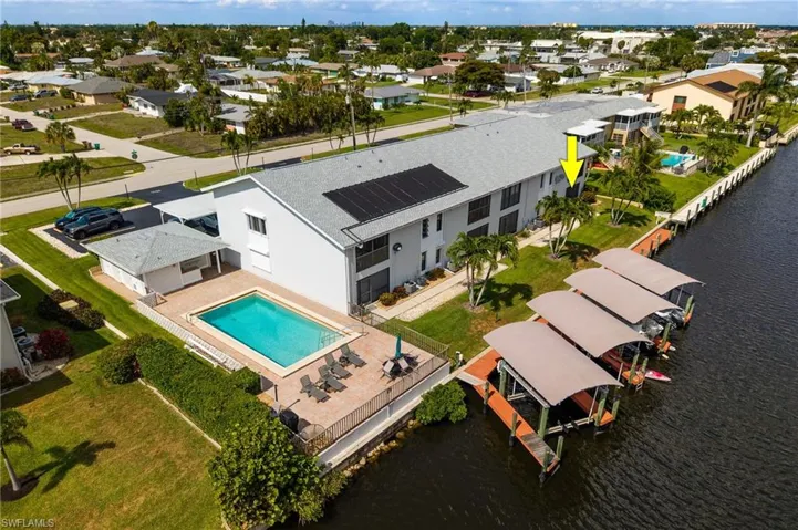 Waterfront property with private boat docks, a swimming pool, and solar panels on the roof