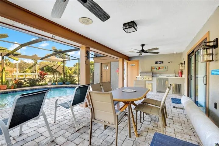 Pool patio with a ceiling fan, an outdoor kitchen / dining area, and a patio area