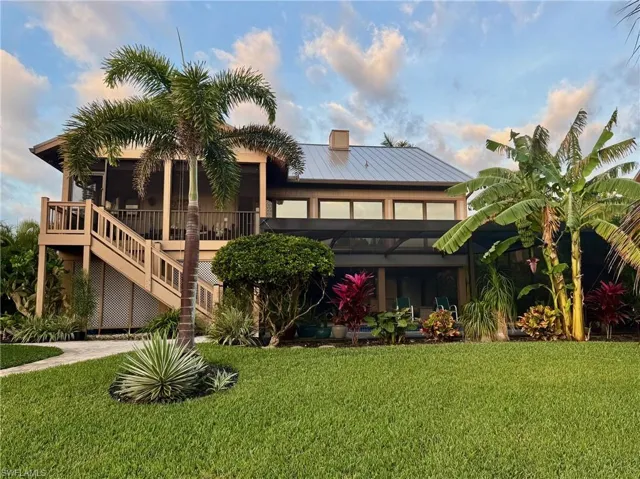 Rear view of house with a yard, a metal roof, a deck, a sunroom, and a chimney