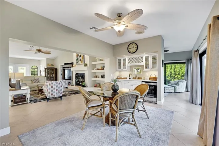Dining room featuring ceiling fan, beverage cooler, a fireplace, and bar area