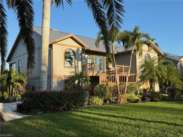 View of front facade featuring a wooden deck, a front yard, and a metal roof