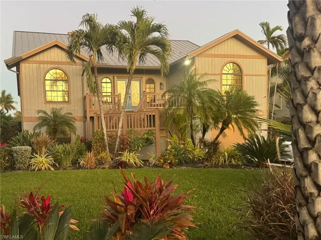 View of front facade with a balcony, a front lawn, and a metal roof