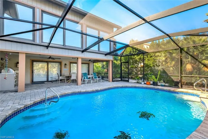 Outdoor pool with a patio, a sunroom, a lanai, and an outdoor kitchen / dining area