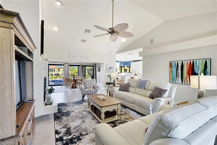 Living room featuring light tile patterned floors, a ceiling fan, lofted ceiling, and recessed lighting