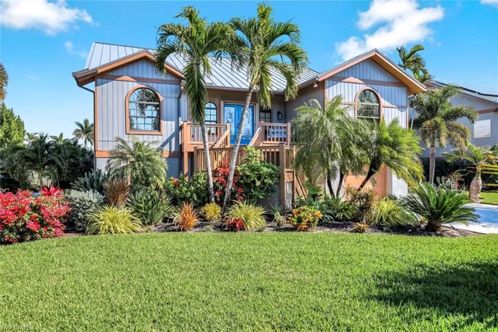 View of front of house featuring a front lawn, a standing seam roof, and a balcony