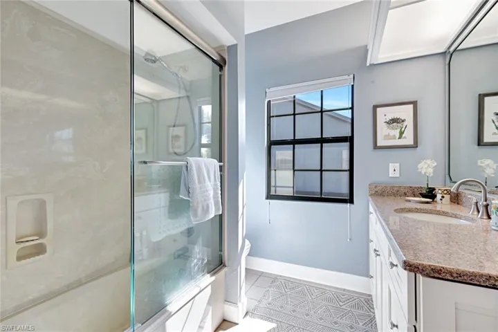 Bathroom featuring vanity, shower / bath combination with glass door, and light tile patterned flooring