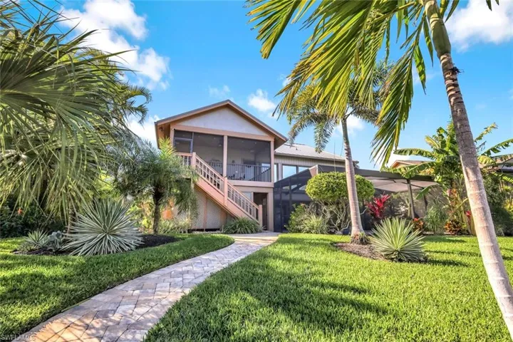 Rear view of property featuring a sunroom, a yard, and stucco siding