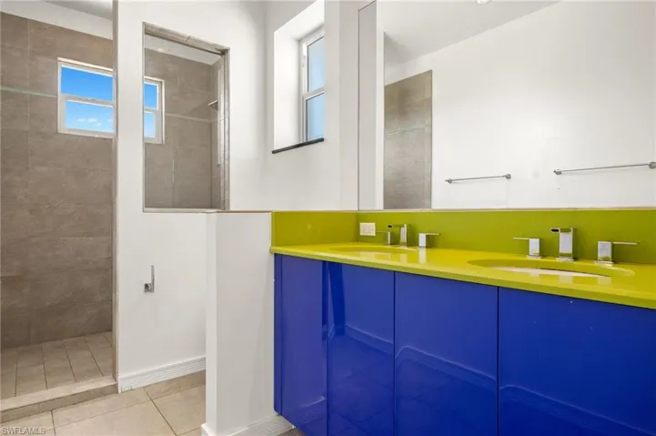 Bathroom with tile patterned flooring, a walk in shower, double vanity, and a sink