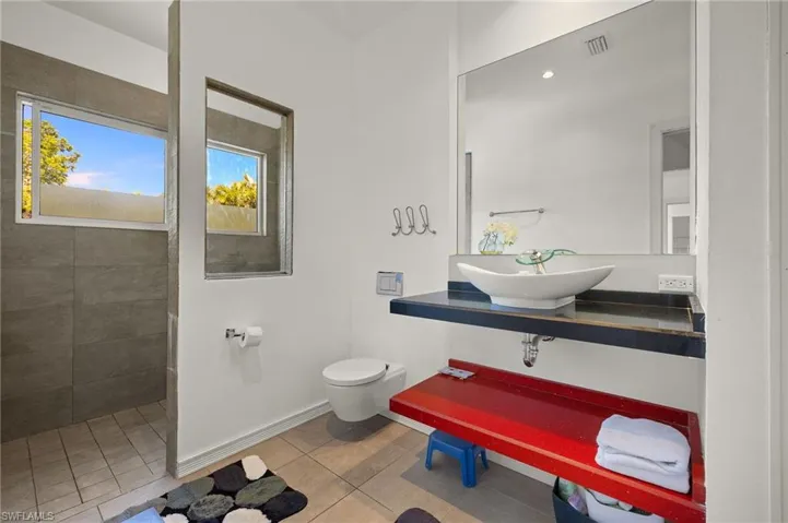 Bathroom with tile patterned floors, visible vents, toilet, a sink, and tiled shower