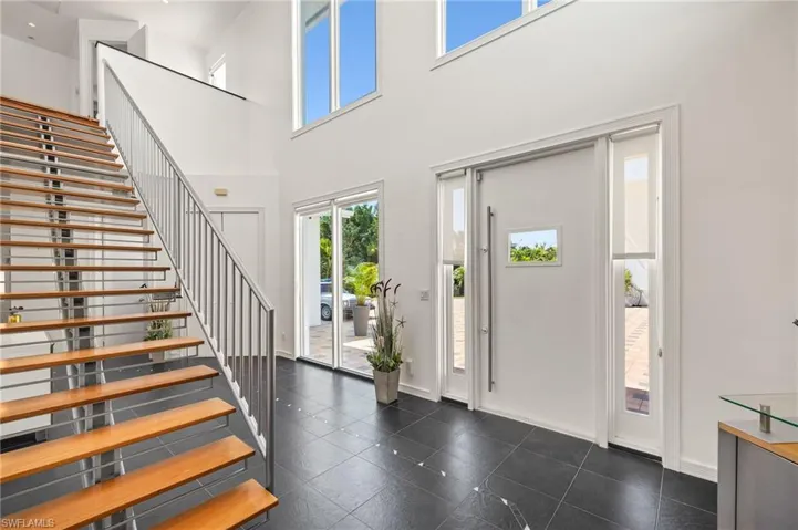 Entryway featuring dark tile patterned floors, baseboards, a towering ceiling, and stairs