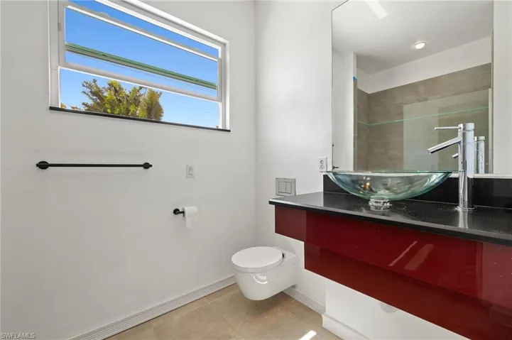 Bathroom featuring tile patterned floors, baseboards, toilet, and vanity