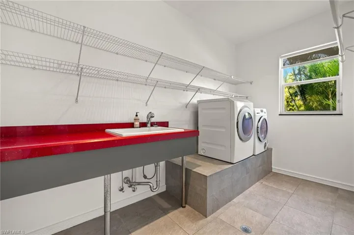 Laundry area with light tile patterned floors, baseboards, laundry area, a sink, and washing machine and dryer