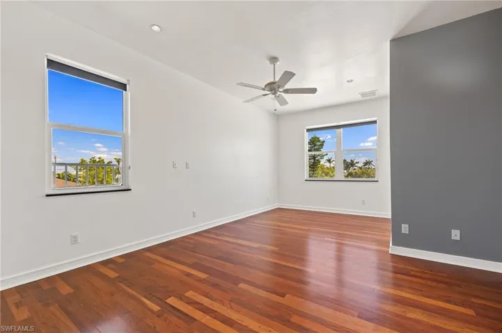 Unfurnished room featuring a wealth of natural light, visible vents, wood finished floors, and ceiling fan