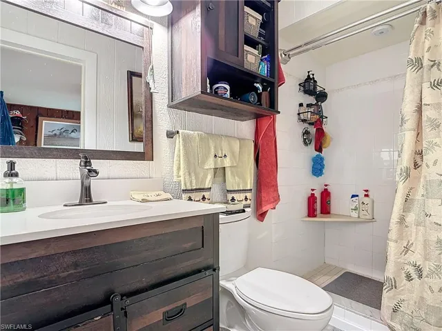 Full bath with toilet, a tile shower, and vanity