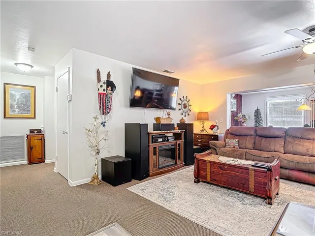 Living area with carpet flooring, ceiling fan, visible vents, and baseboards