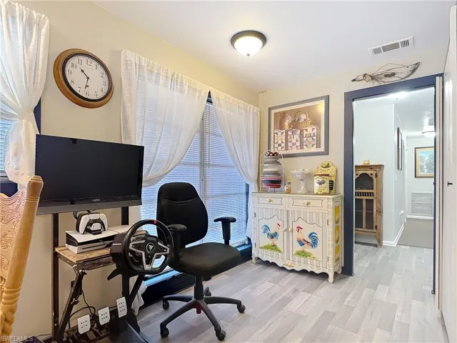 Office with light wood-style floors, visible vents, and baseboards