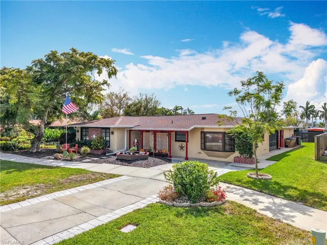 Ranch-style house featuring driveway, fence, a front lawn, and stucco siding