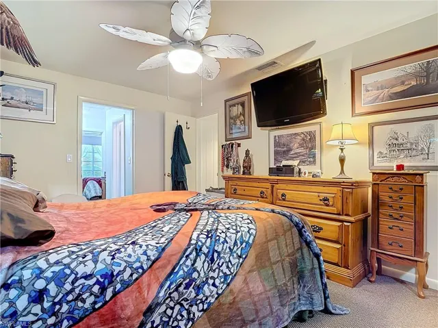 Carpeted bedroom with visible vents and ceiling fan